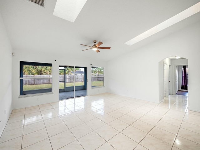 unfurnished room with light tile patterned floors, ceiling fan, and vaulted ceiling with skylight