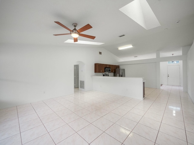 unfurnished living room featuring ceiling fan, light tile patterned floors, and vaulted ceiling