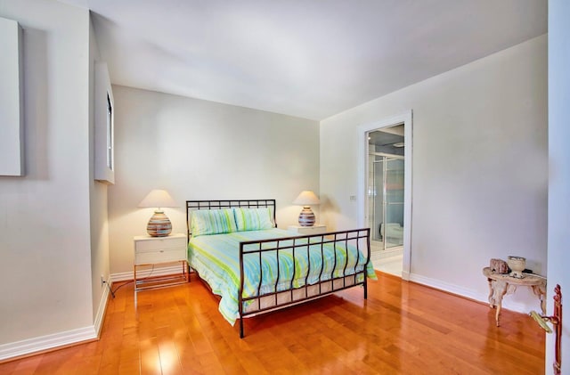 bedroom featuring connected bathroom and hardwood / wood-style flooring