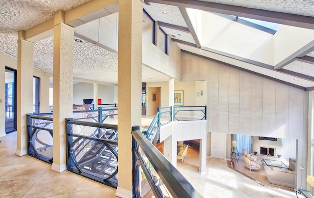 hall featuring tile patterned flooring, a towering ceiling, and a textured ceiling