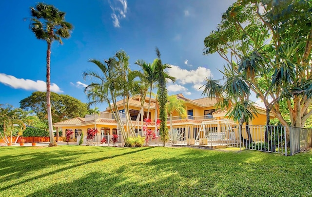 rear view of property featuring a lawn and a balcony