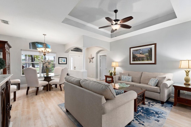 living room with ceiling fan with notable chandelier, a raised ceiling, and light hardwood / wood-style flooring