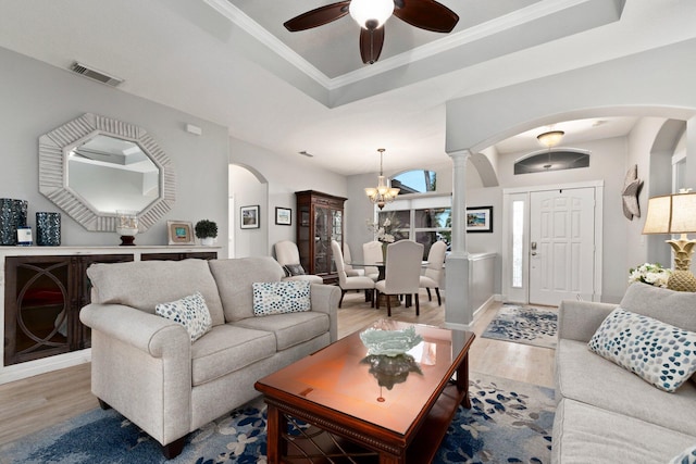 living room featuring hardwood / wood-style floors, ceiling fan with notable chandelier, a raised ceiling, and ornamental molding