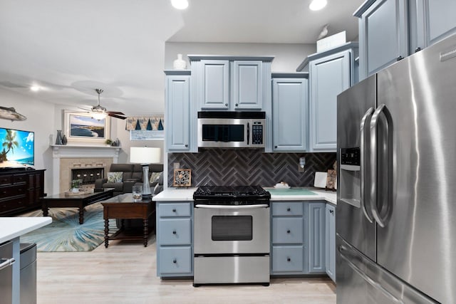 kitchen featuring backsplash, stainless steel appliances, ceiling fan, and light hardwood / wood-style floors