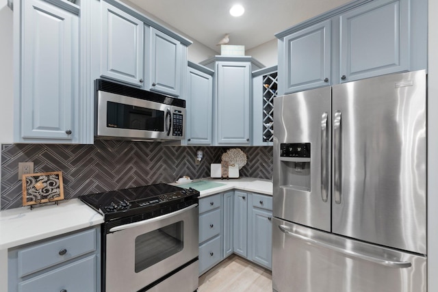 kitchen featuring light wood-type flooring, backsplash, and appliances with stainless steel finishes