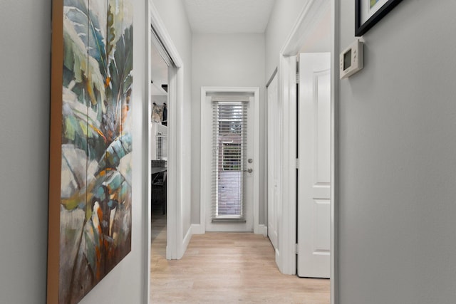 hallway with light hardwood / wood-style flooring and a textured ceiling