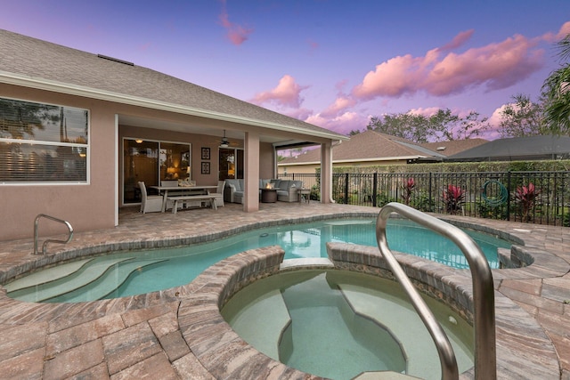 pool at dusk featuring outdoor lounge area, ceiling fan, an in ground hot tub, and a patio