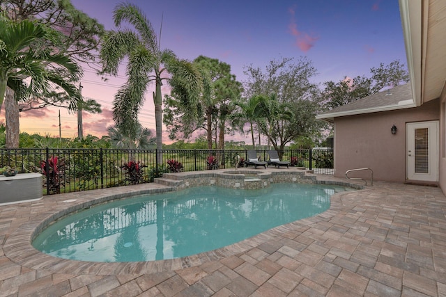 pool at dusk with a patio area and an in ground hot tub