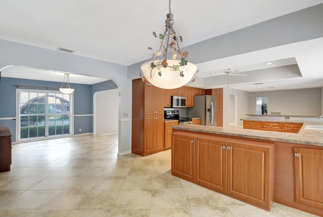 kitchen with sink, hanging light fixtures, ceiling fan, a tray ceiling, and stainless steel appliances