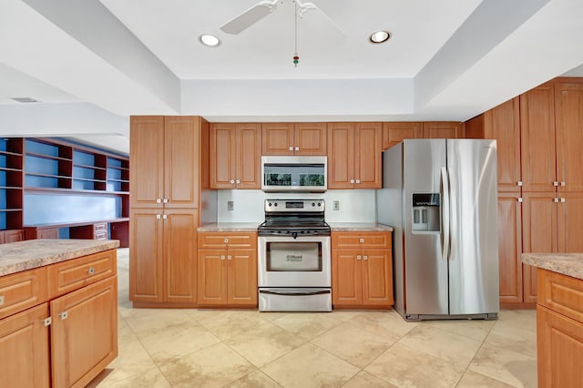 kitchen with ceiling fan, light stone counters, light tile patterned floors, and appliances with stainless steel finishes