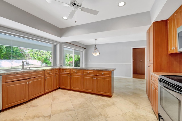 kitchen featuring sink, kitchen peninsula, ceiling fan, decorative light fixtures, and range