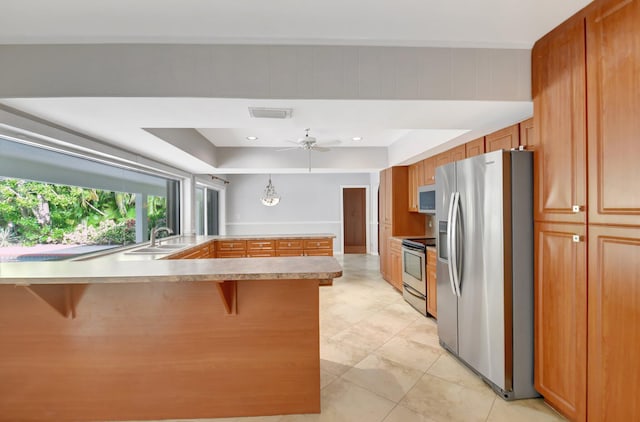 kitchen featuring ceiling fan, sink, kitchen peninsula, a breakfast bar area, and appliances with stainless steel finishes