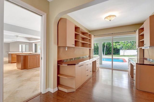 kitchen with a center island, light hardwood / wood-style flooring, ceiling fan, and backsplash