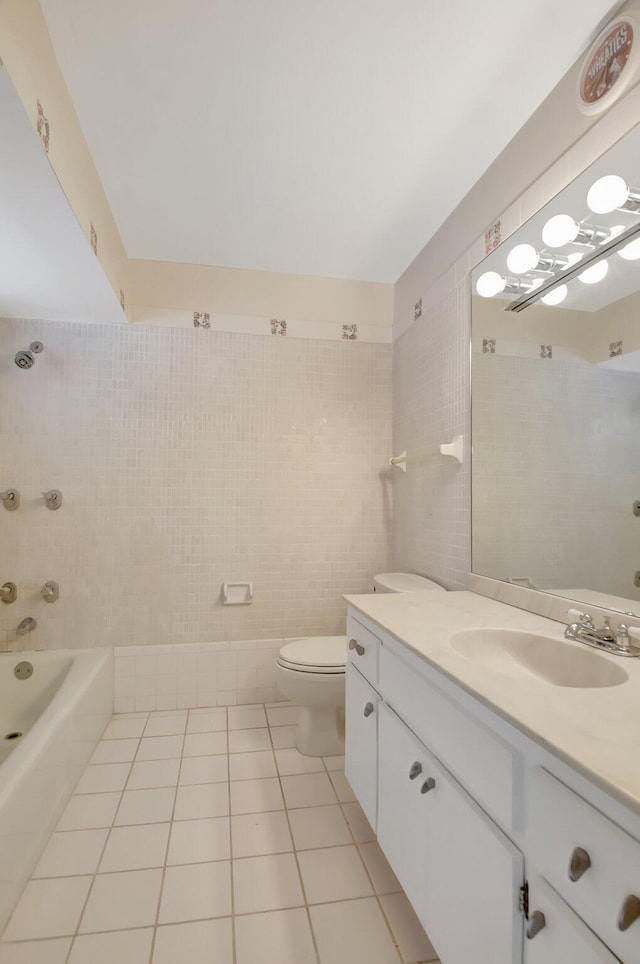 full bathroom with vanity, tile patterned flooring, tiled shower / bath combo, toilet, and tile walls