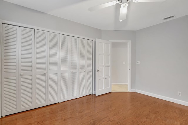 unfurnished bedroom featuring hardwood / wood-style floors, ceiling fan, and a closet