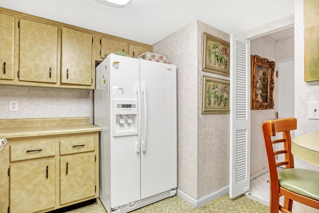 kitchen with white refrigerator with ice dispenser and a textured ceiling