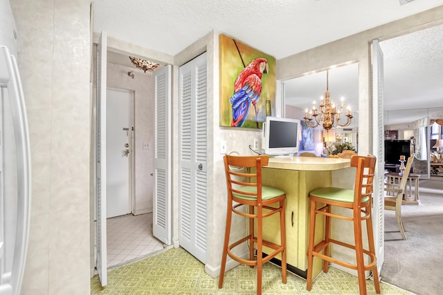 kitchen featuring white fridge, light colored carpet, a textured ceiling, and an inviting chandelier