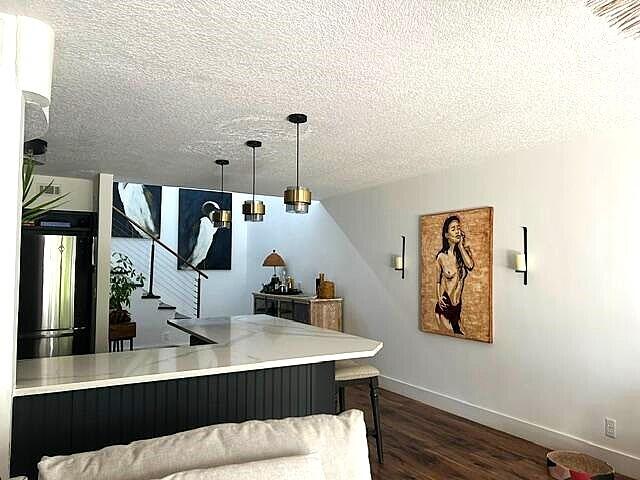 bar featuring a textured ceiling, dark hardwood / wood-style flooring, and decorative light fixtures