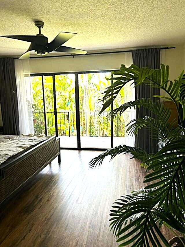 bedroom with access to exterior, a textured ceiling, and hardwood / wood-style flooring