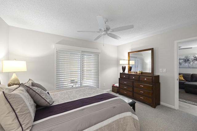 carpeted bedroom featuring ceiling fan and a textured ceiling