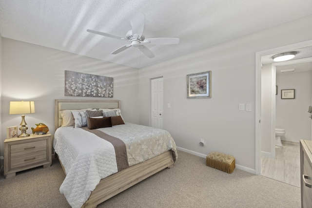 carpeted bedroom with a textured ceiling, ensuite bathroom, and ceiling fan