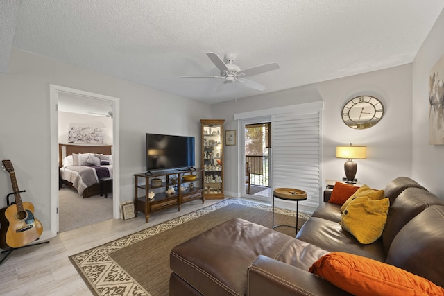 living room with ceiling fan and a textured ceiling