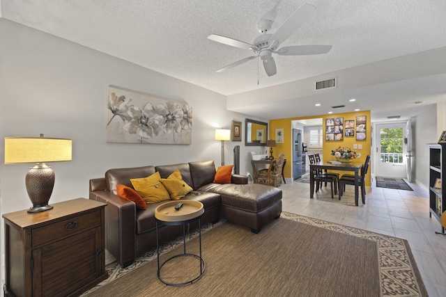 living room with ceiling fan and a textured ceiling