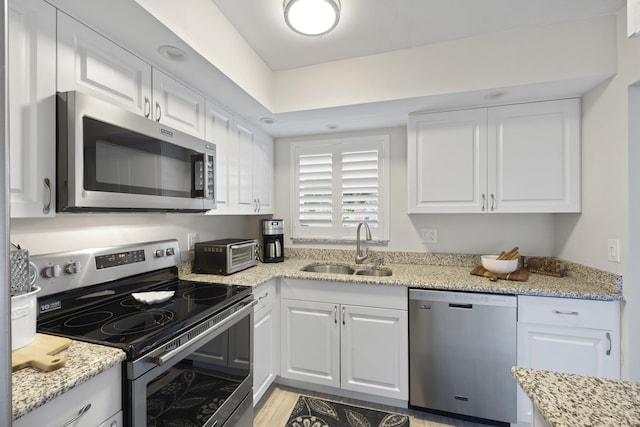 kitchen featuring light stone countertops, white cabinetry, sink, and appliances with stainless steel finishes