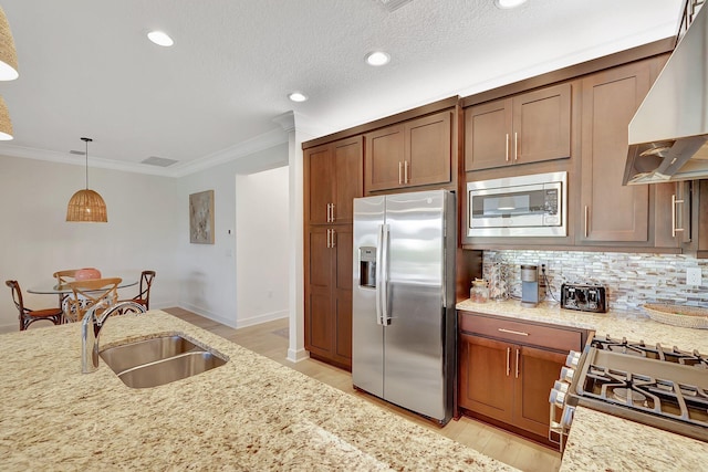 kitchen with sink, stainless steel appliances, light stone counters, range hood, and decorative light fixtures