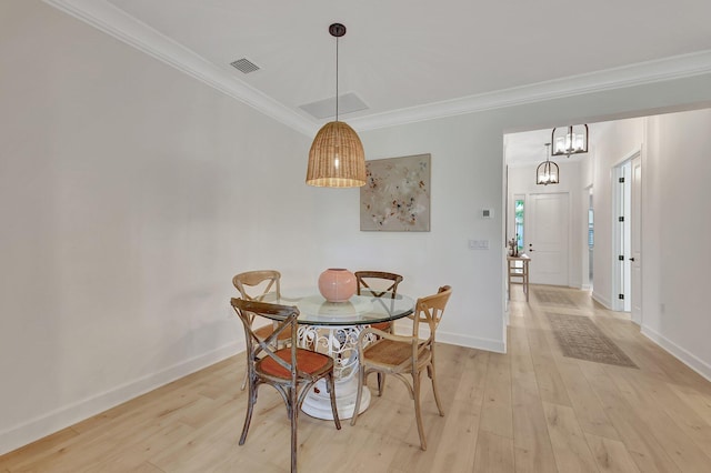 dining area with light hardwood / wood-style flooring, a notable chandelier, and ornamental molding