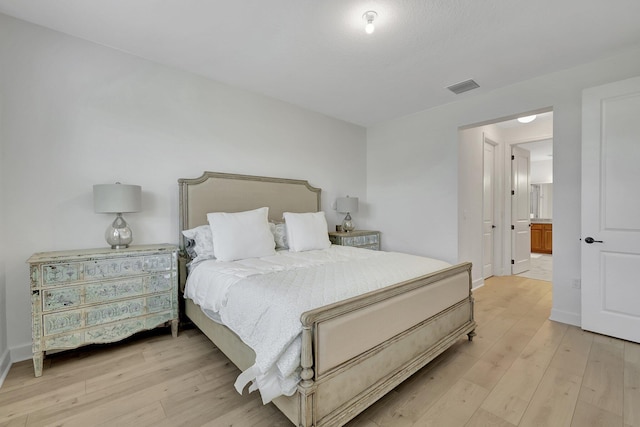 bedroom featuring light wood-type flooring and ensuite bath