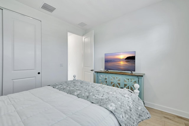 bedroom with light hardwood / wood-style floors and a closet