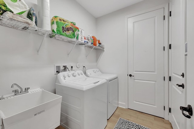 clothes washing area featuring light hardwood / wood-style floors, washing machine and dryer, and sink