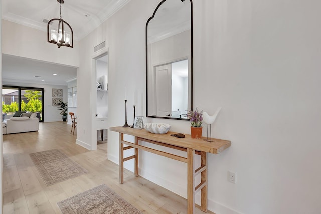 foyer featuring light hardwood / wood-style floors, crown molding, and a chandelier