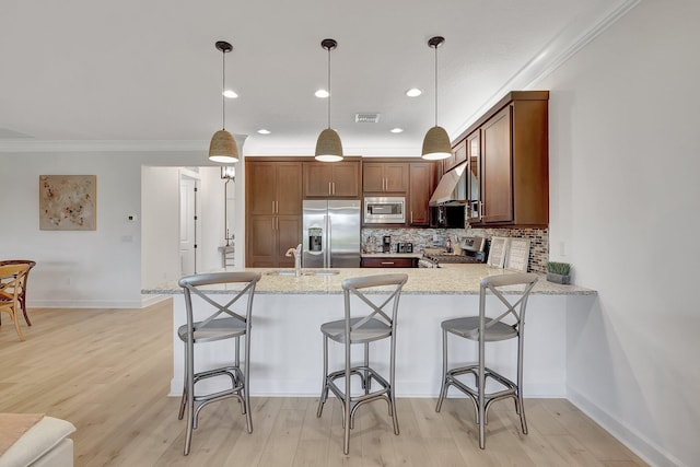 kitchen featuring hanging light fixtures, range hood, built in appliances, kitchen peninsula, and ornamental molding