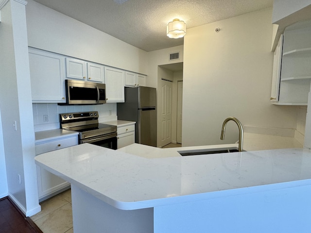 kitchen with white cabinets, sink, kitchen peninsula, and stainless steel appliances