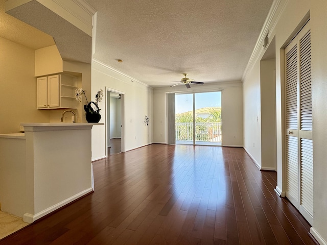 unfurnished living room featuring ceiling fan, crown molding, dark wood-type flooring, and a textured ceiling