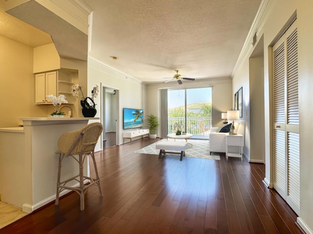 living room featuring ceiling fan, crown molding, dark hardwood / wood-style floors, and a textured ceiling