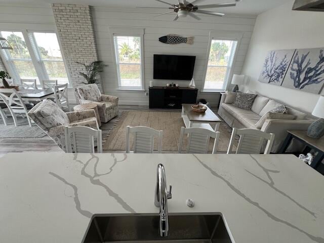 living room featuring a wealth of natural light, sink, ceiling fan, and wood walls