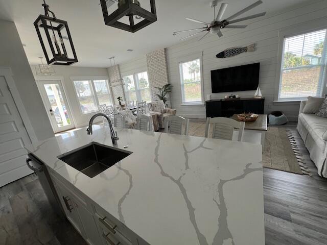 kitchen with decorative light fixtures, light stone countertops, sink, and dark wood-type flooring