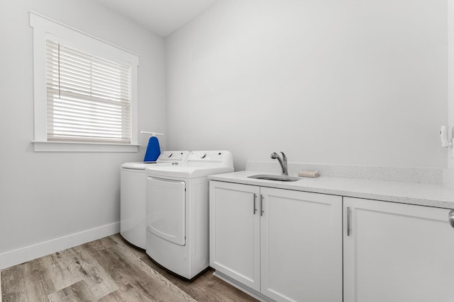 washroom with cabinets, sink, washer and dryer, and light hardwood / wood-style floors