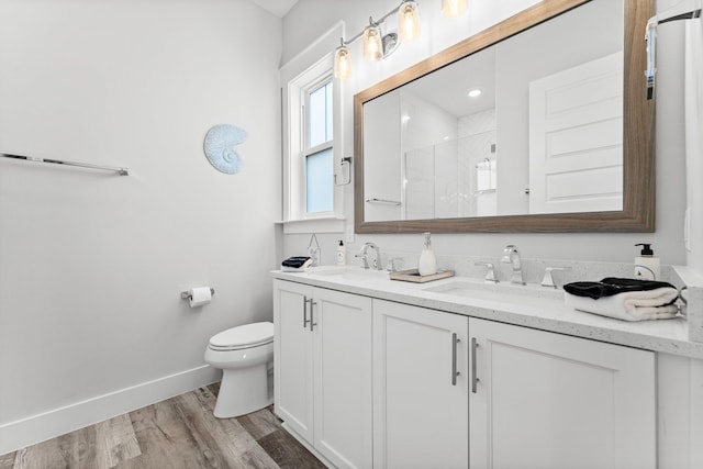 bathroom featuring a shower with door, vanity, hardwood / wood-style floors, and toilet