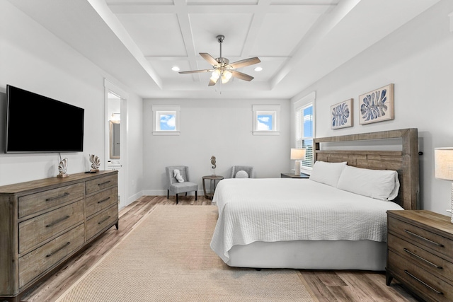 bedroom featuring ceiling fan, light hardwood / wood-style floors, ensuite bathroom, and coffered ceiling