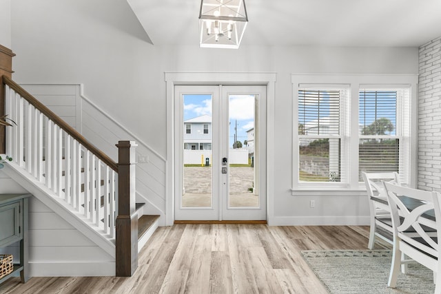 entryway with french doors, a chandelier, and light hardwood / wood-style flooring