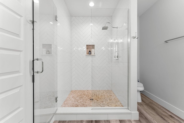 bathroom featuring hardwood / wood-style floors, toilet, and a shower with shower door