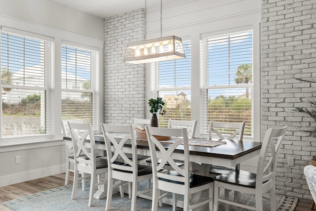 dining area featuring brick wall and hardwood / wood-style flooring