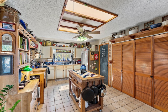 kitchen with ceiling fan, high end fridge, light tile patterned floors, and sink