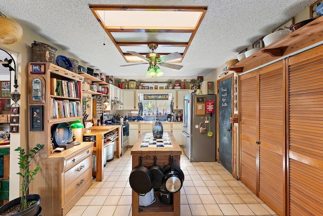 kitchen featuring a textured ceiling, stainless steel appliances, ceiling fan, butcher block countertops, and light tile patterned flooring