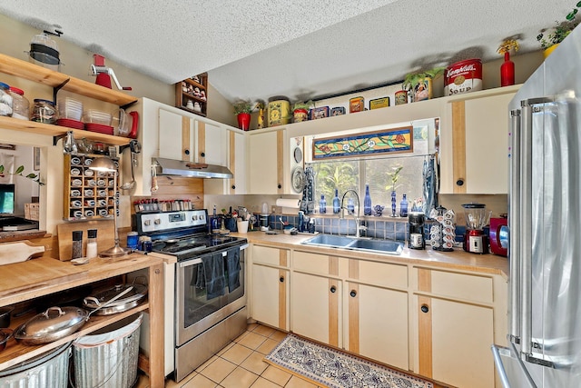 kitchen featuring appliances with stainless steel finishes, a textured ceiling, light tile patterned floors, and sink