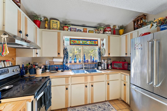 kitchen featuring sink, black range with electric cooktop, a textured ceiling, high end fridge, and light tile patterned floors